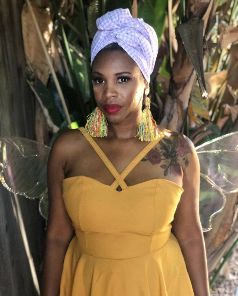 woman in yellow outfit with scarf on hair for Black Fae Day